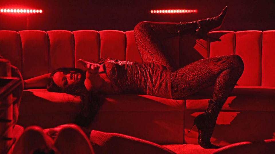 Rihanna is seen during Rihanna's Savage X Fenty Show Vol. 3 lying in a red lit room, lying back on a couch