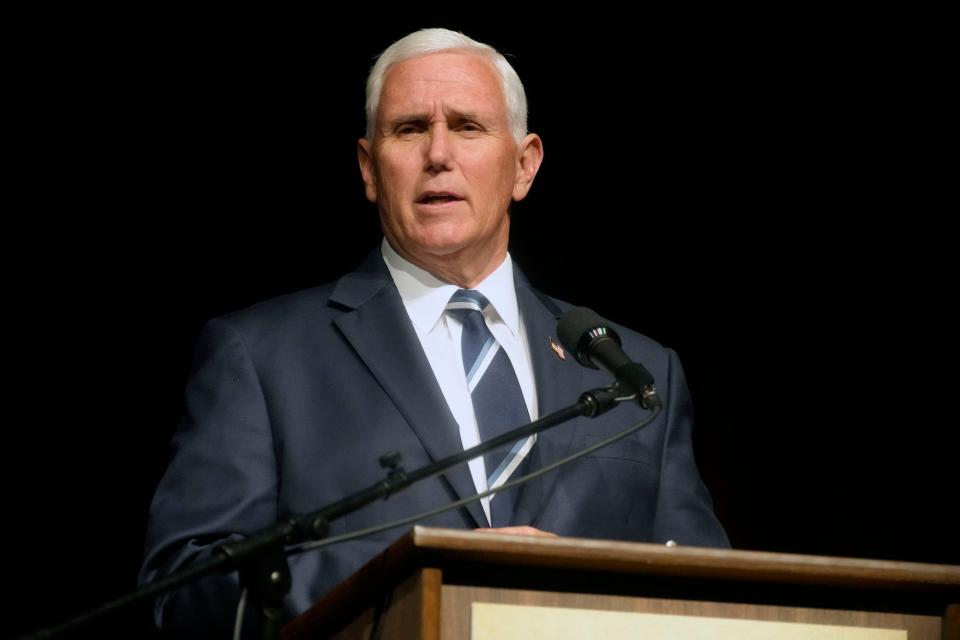 Former Vice President Mike Pence wearing a gray suit and gray tie, speaking at a lectern