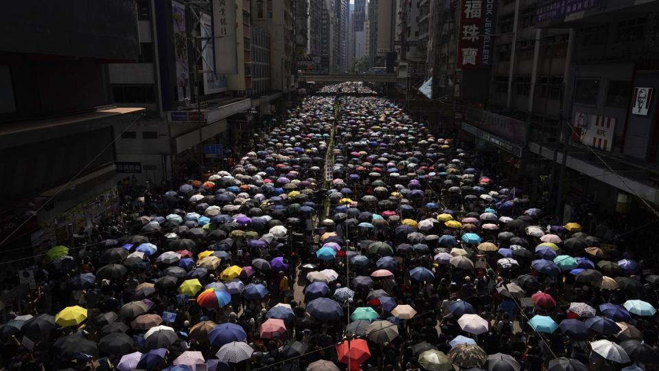 Tausende Hongkonger ziehen mit Regenschirmen über eine Straße. Foto: Vincent Yu/AP