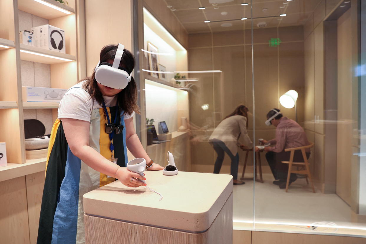 Yuxi Wang, a product marketing manager at Meta, demonstrates using the oculus headset with the Horizons Work Rooms program during a preview of the inaugural physical store of Facebook-owner Meta Platforms Inc in Burlingame, California, U.S. May 4, 2022.  REUTERS/Brittany Hosea-Small