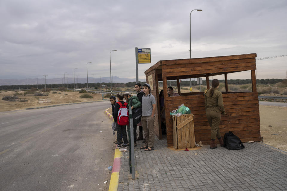 Young Jewish settlers wait for transportation to go to school next to the West Bank outpost of Beit Hogla, Thursday, Feb. 16, 2023. Israel's new ultranationalist government declared last week that it would legalize 10 unauthorized outposts in the occupied West Bank. The rare move intensified the country's defiance of international pressure and opened an aggressive new front of Israeli expansion into the West Bank, which Israel captured in the 1967 Mideast war. (AP Photo/Ohad Zwigenberg)