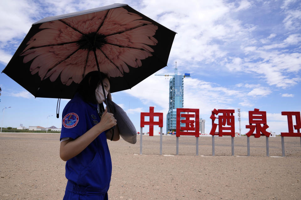 A worker holds an umbrella near the Shenzhou-12 spacecraft covered on the launch pad with the Chinese characters reading "China Jiuquan Satellite Launch Center" near Jiuquan on Wednesday, June 16, 2021. China plans to launch three astronauts onboard the Shenzhou-12 spacecraft, who will be the first crew members to live on China's new orbiting space station Tianhe, or Heavenly Harmony, from the Jiuquan Satellite Launch Center in northwest China. (AP Photo/Ng Han Guan)