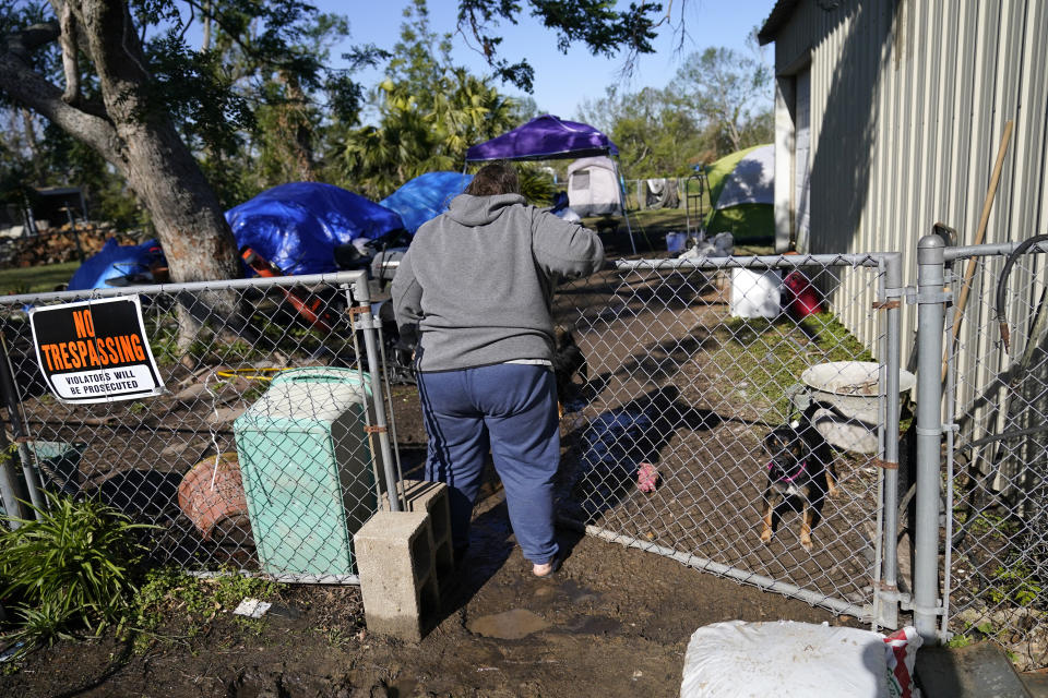 Sherry Bourque enters the back yard of her fathers heavily damaged home, where she is living in a tent, in the aftermath of both Hurricane Laura and Hurricane Delta, in Lake Charles, La., Friday, Dec. 4, 2020. (AP Photo/Gerald Herbert)