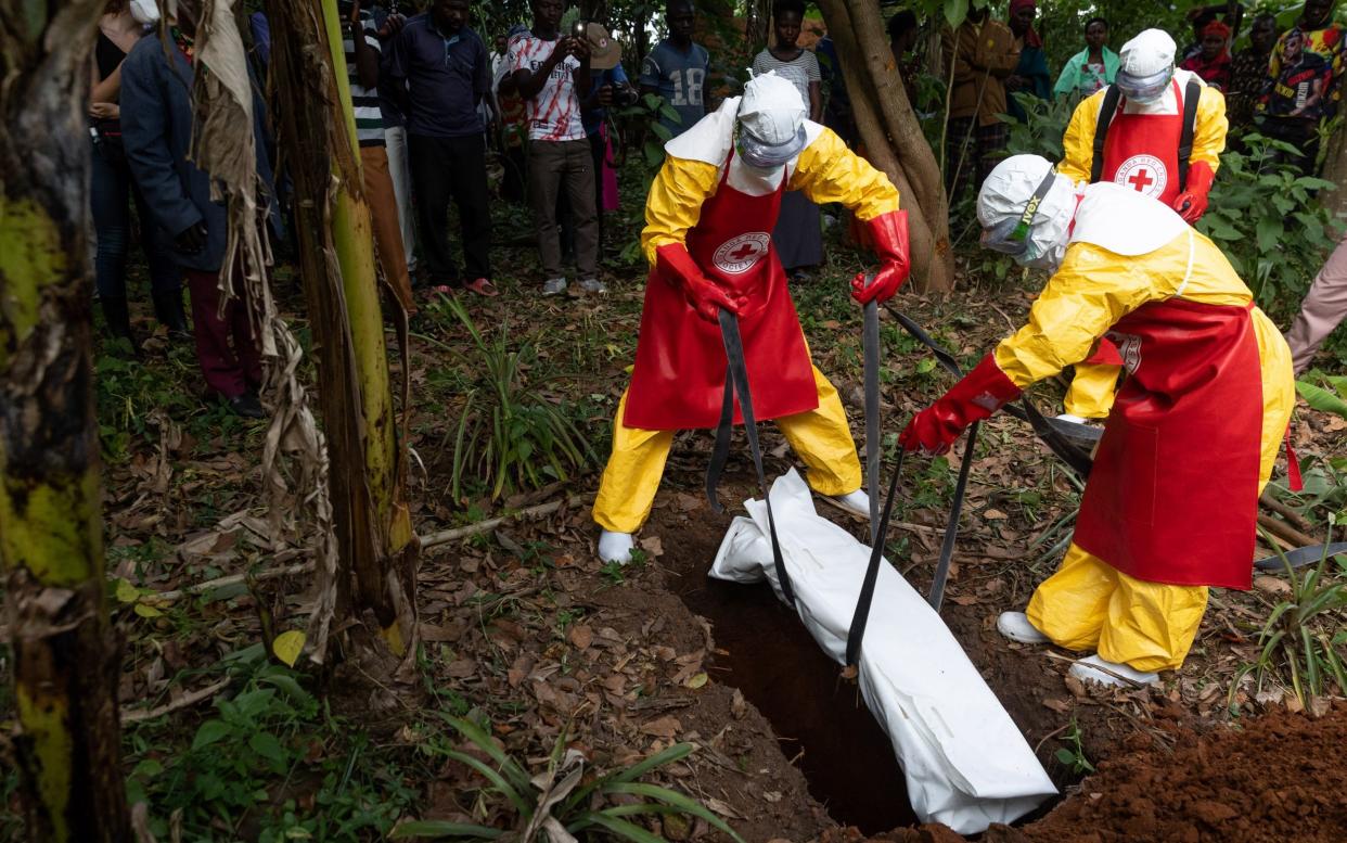Red Cross workers place a body bag, containing the body of a 3-year-old suspected Ebola victim, into a grave in Mubende - Luke Dray/Getty Images