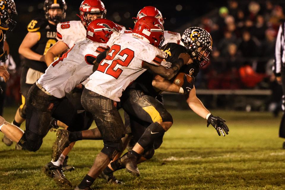 Garfield running back Anthony Demma drags several defensive players as he carries the ball during Saturday night's regional quarterfinal playoff game against Bellaire High School.