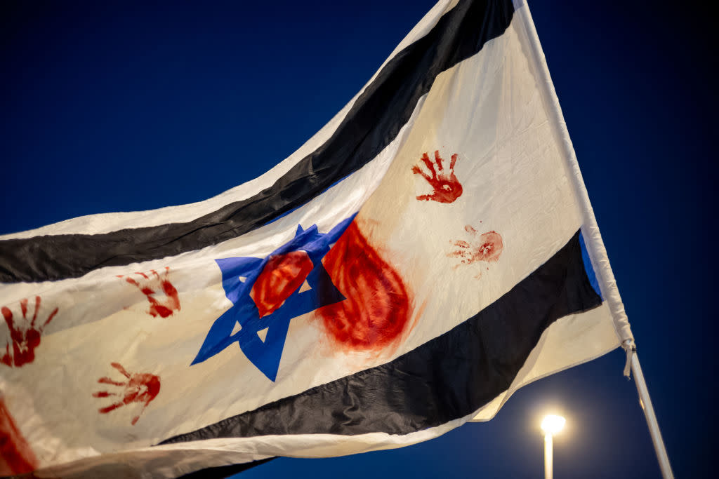 The Israeli flag is raised in black color with red handprints symbolizing blood in a demonstration near the Knesset, on March 31, 2024, in Jerusalem, Israel.<span class="copyright">Yahel Gazit—Middle East Images/Getty</span>