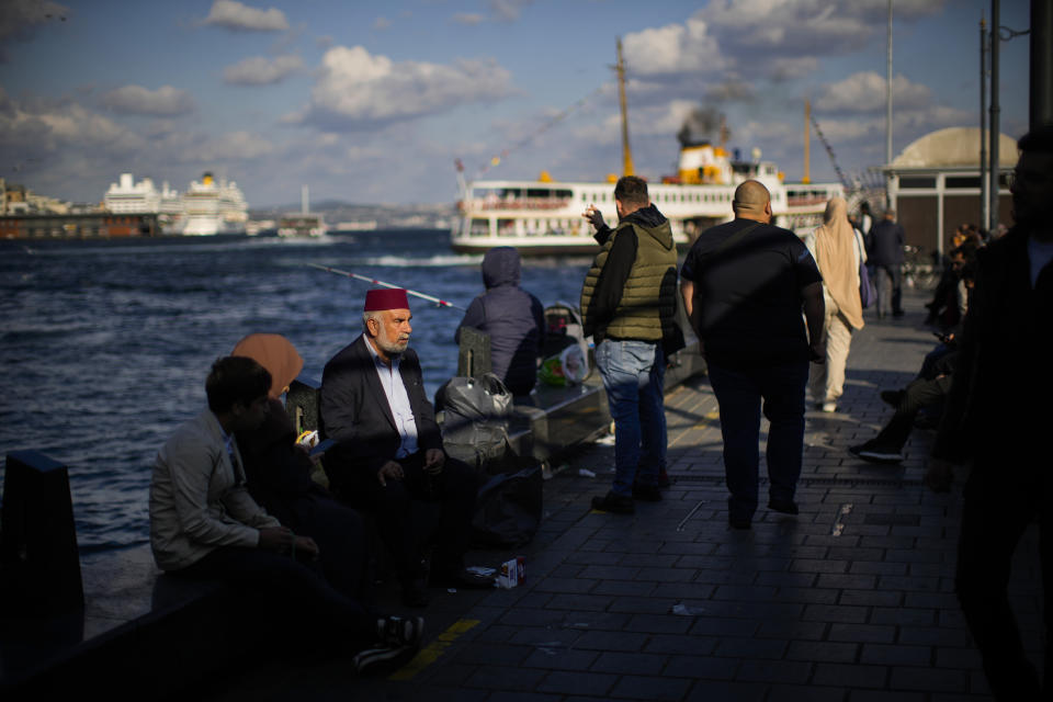 People sit at a promenade next to a ferry terminal at Eminonu district in Istanbul, Turkey, Friday, Oct. 28, 2022. Turkish President Recep Tayyip Erdogan on Friday laid out his vision for Turkey in the next century, promising a new constitution that would guarantee the rights and freedoms of citizens. (AP Photo/Francisco Seco)