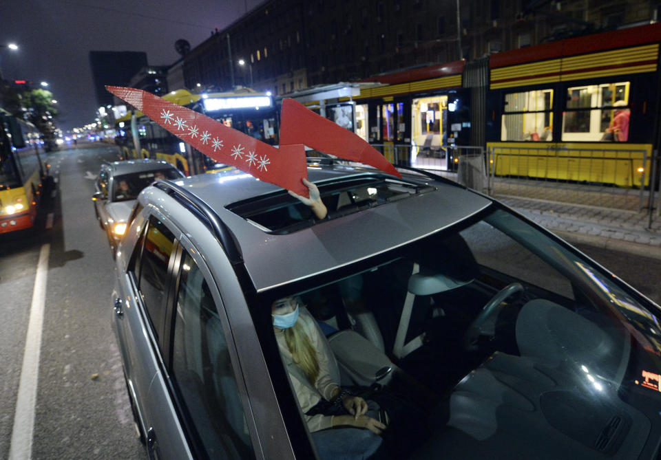 Protesters inside a car hold the sign of the women's protest action in downtown Warsaw, Monday, Nov. 9, 2020, on the 12th straight day of anti-government protests that were triggered by the tightening of Poland's strict abortion law and are continuing despite a anti-COVID-19 ban on public gatherings. (AP Photo/Czarek Sokolowski)