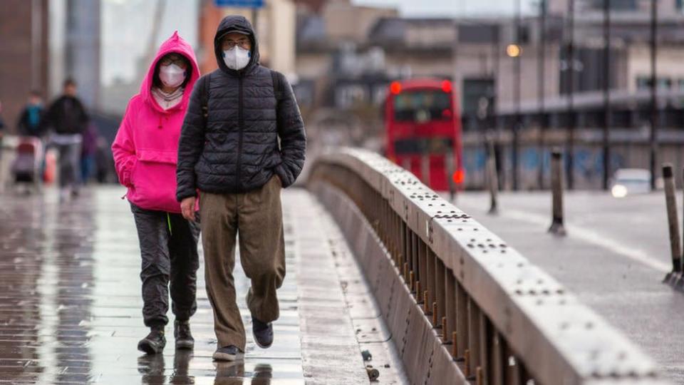 Dos personas caminan por Londres con mascarilla.