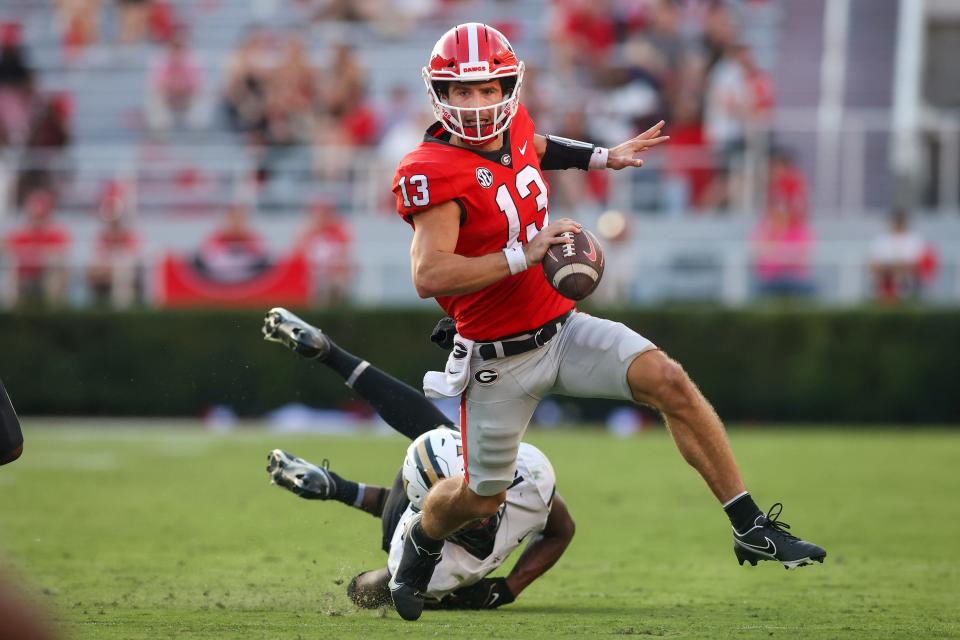 FILE - Georgia quarterback Stetson Bennett (13) scrambles away from Vanderbilt linebacker CJ Taylor (13) in the second half of an NCAA college football game Saturday, Oct. 15, 2022, in Athens, Ga. Defending-champion Georgia will host the Buckeyes in its own backyard during the Peach Bowl on New Year's Eve. It's Bennett who Ohio State's defense must center their focus around, Ohio State coach Ryan Day says. (AP Photo/Brett Davis, File)