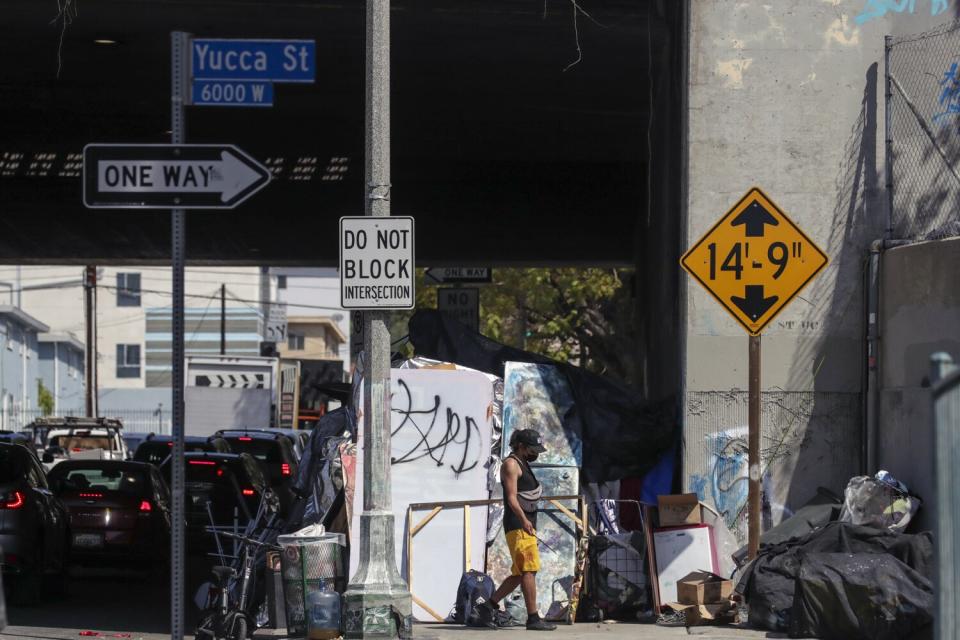 Tents and belongings sit under a freeway.