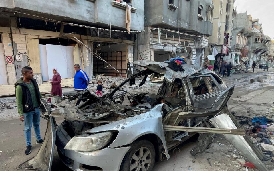 Onlookers check the car in which three sons of Hamas leader Ismail Haniyeh were killed