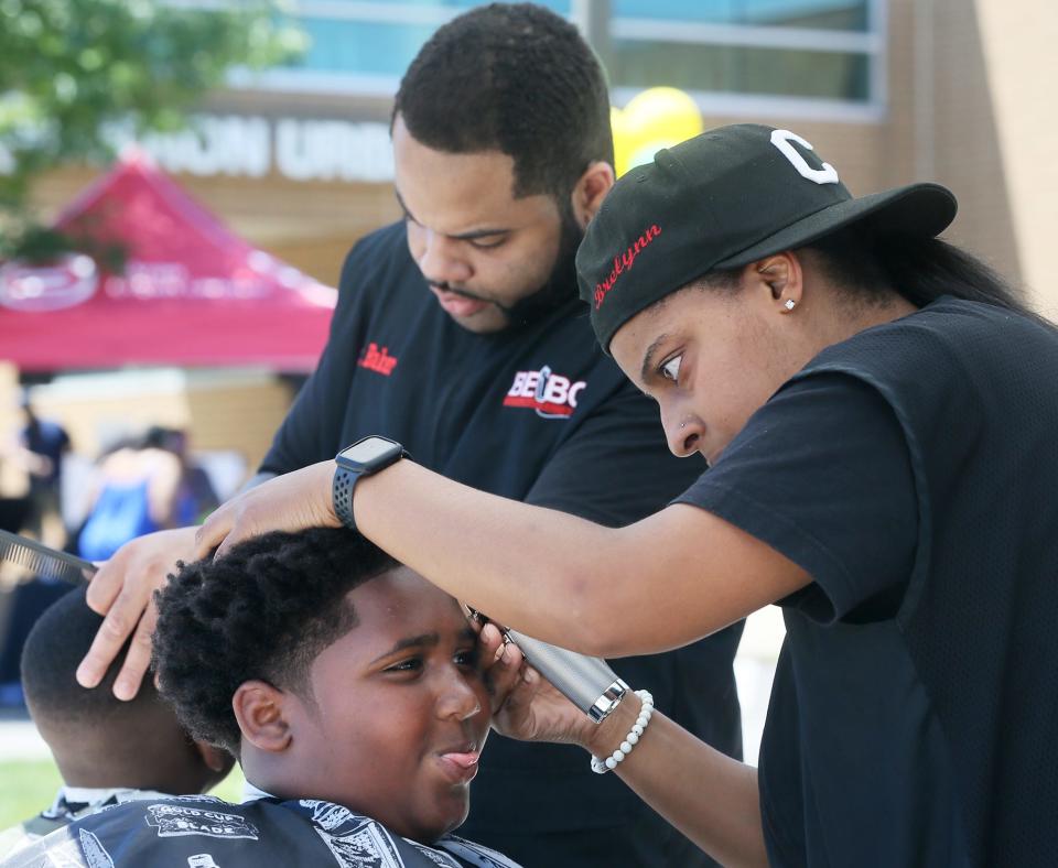 Braylon Solomon, 12, gets a haircut from Brea Forney from Beyond Expectations Barber College as Don Baker II gives a haircut in the background during the Juneteenth  Vax and Vote Blitz at the Akron Urban League in Akron on Friday, June 17, 2022.