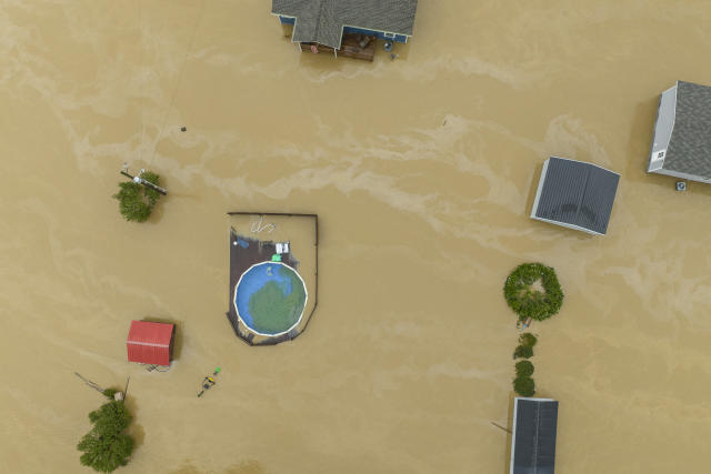 An aerial view of flooded homes and structures, with a few trees poking above the muddy waters.