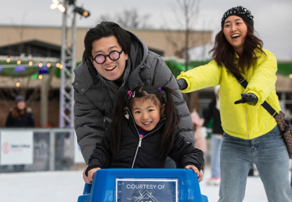 Rune Noguchi pushes his daughter Alice Noguchi on a skate helper as his wife, Wakako Noguchi, skates behind them inside the ice rink during the weekend-long Winter Blast Royal Oak event on Saturday, Feb. 3, 2024.