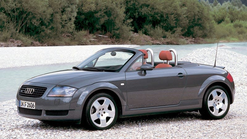 A photo of a grey Audi TT by a river. 