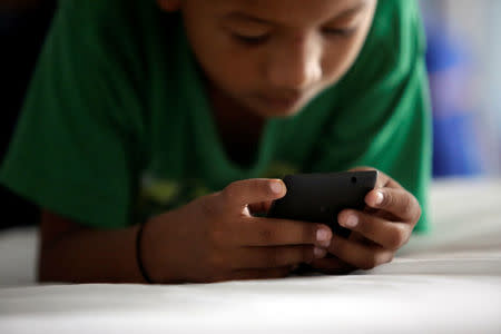 A Salvadoran migrant child plays with a phone at the Senda de Vida migrant shelter in Reynosa, in Tamaulipas state, Mexico June 22, 2018. Picture taken June 22, 2018. REUTERS/Daniel Becerril