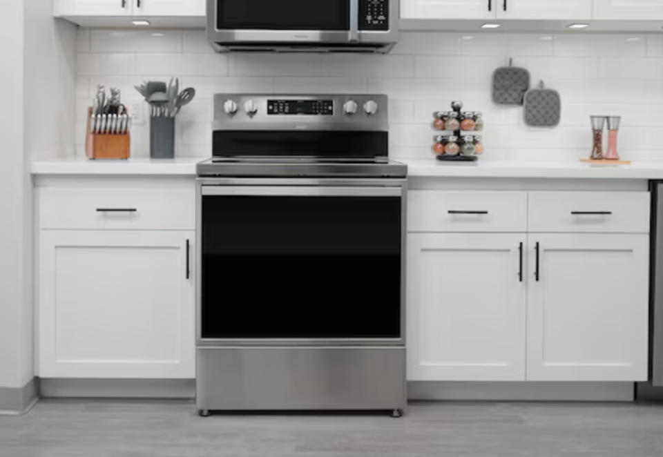 Modern kitchen with stainless steel oven in the center of white cabinets