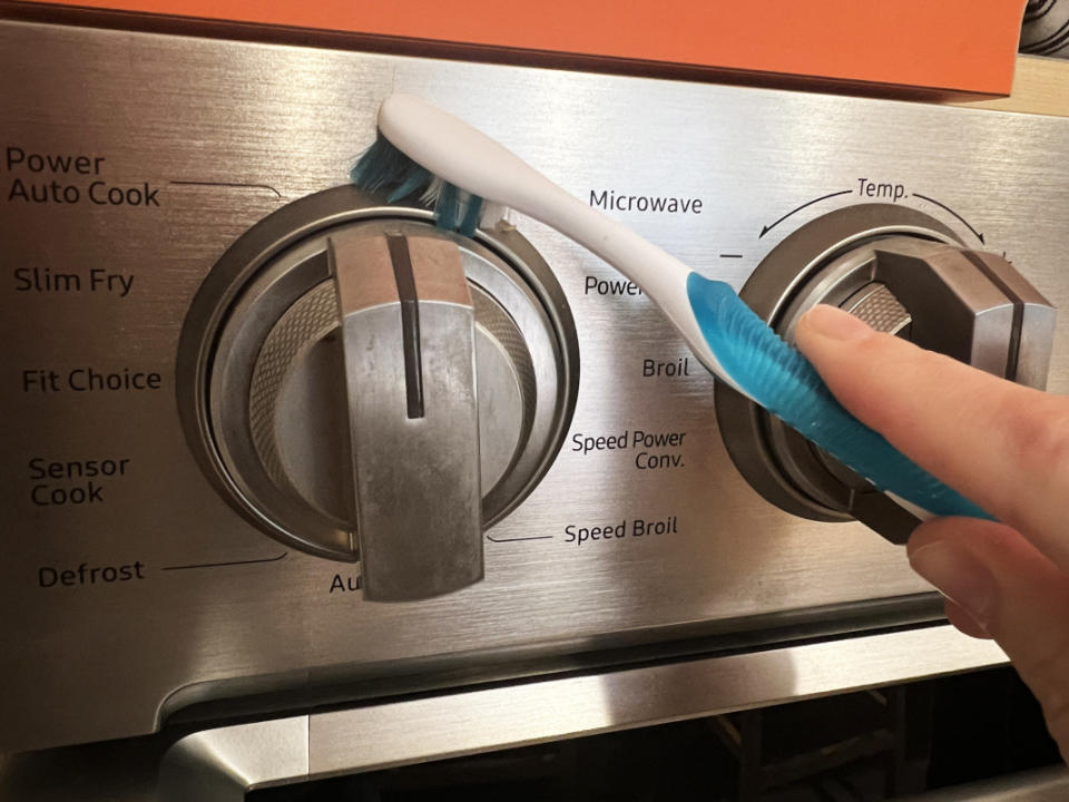 Using a toothbrush to clean crevices on a stainless steel oven.<p>Emily Fazio</p>