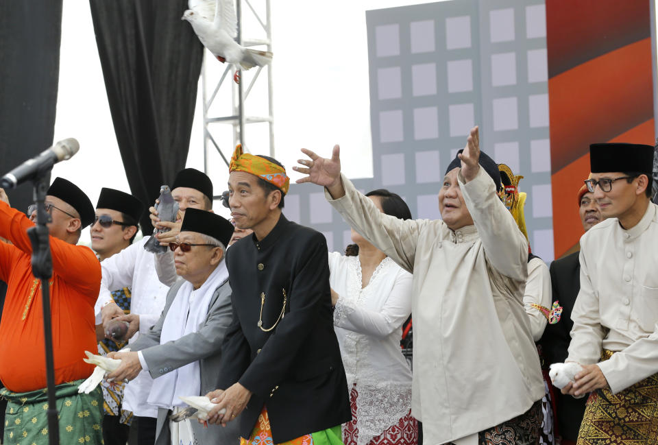 Indonesian President Joko Widodo, center left, and his running mate Ma'ruf Amin, left, and his contender Prabowo Subianto, center right, with his running mate Sandiaga Uno, right, release birds during a ceremony marking the kick off of the campaign period for next year's election in Jakarta, Indonesia, Sunday, Sept. 23, 2018. Indonesia is set to hold its presidential and parliamentary election poll in April 2019.(AP Photo/Tatan Syuflana)