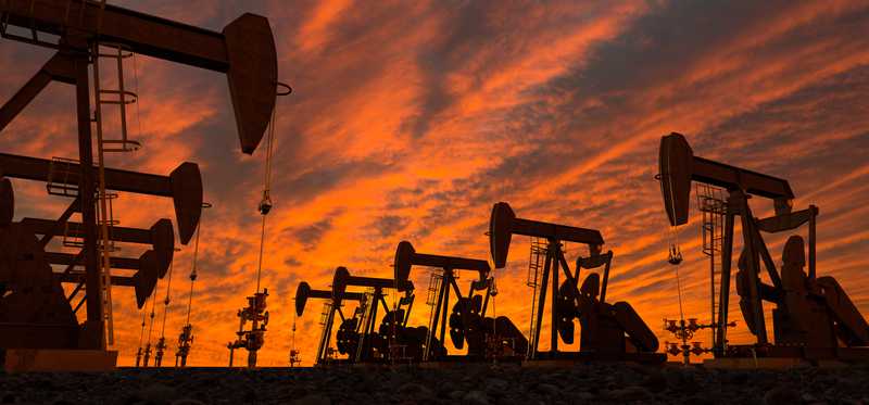 Several oil pumps in a row at dusk.