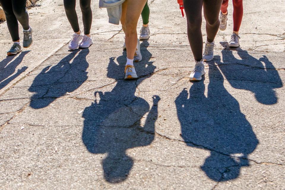 Shadows of multiple people walking on concrete.