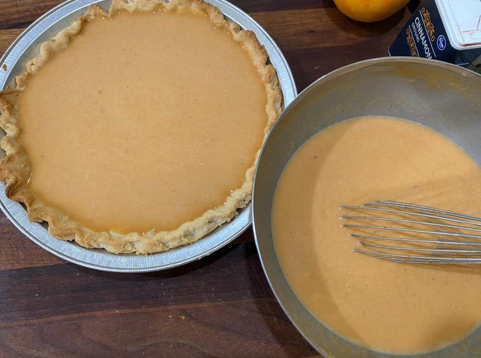 unbaked pumpkin pie sitting next to a bowl with extra pie filling