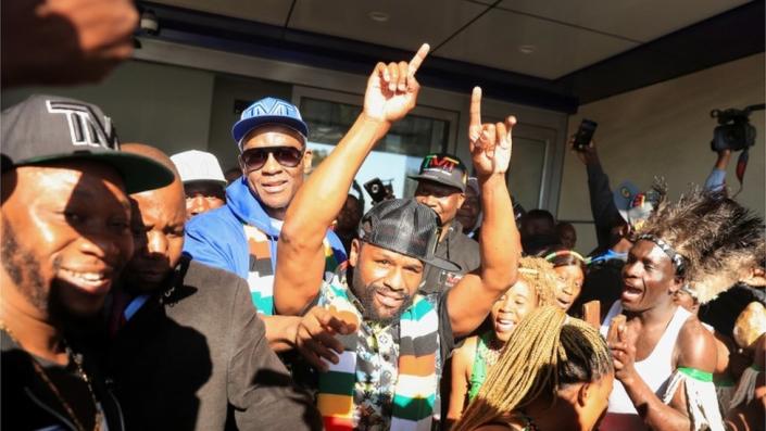 Floyd Mayweather gestures to fans upon his arrival at Robert Gabriel Mugabe International Airport in Harare, Zimbabwe, on 13 July.