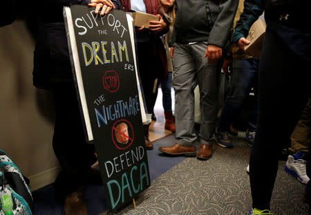 Protesters calling for an immigration bill addressing the so-called Dreamers, young adults who were brought to the United States as children, carry a sign supporting DACA in the office of Senator Chuck Grassley on Capitol Hill in Washington, U.S., January 16, 2018. REUTERS/Joshua Roberts