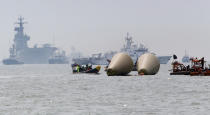 Searchers and divers look for people believed to have been trapped in the sunken ferry boat Sewol near the buoys which were installed to mark the vessel in the water off the southern coast near Jindo, south of Seoul, South Korea, Tuesday, April 22, 2014. One by one, coast guard officers carried the newly arrived bodies covered in white sheets from a boat to a tent on the dock of this island, the first step in identifying a sharply rising number of corpses from the South Korean ferry that sank nearly a week ago. (AP Photo/Lee Jin-man)