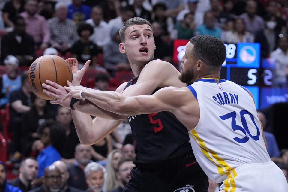 Miami Heat forward Nikola Jovic (5) looks for an opening past Golden State Warriors guard Stephen Curry (30) during the first half of an NBA basketball game, Tuesday, March 26, 2024, in Miami. (AP Photo/Wilfredo Lee)