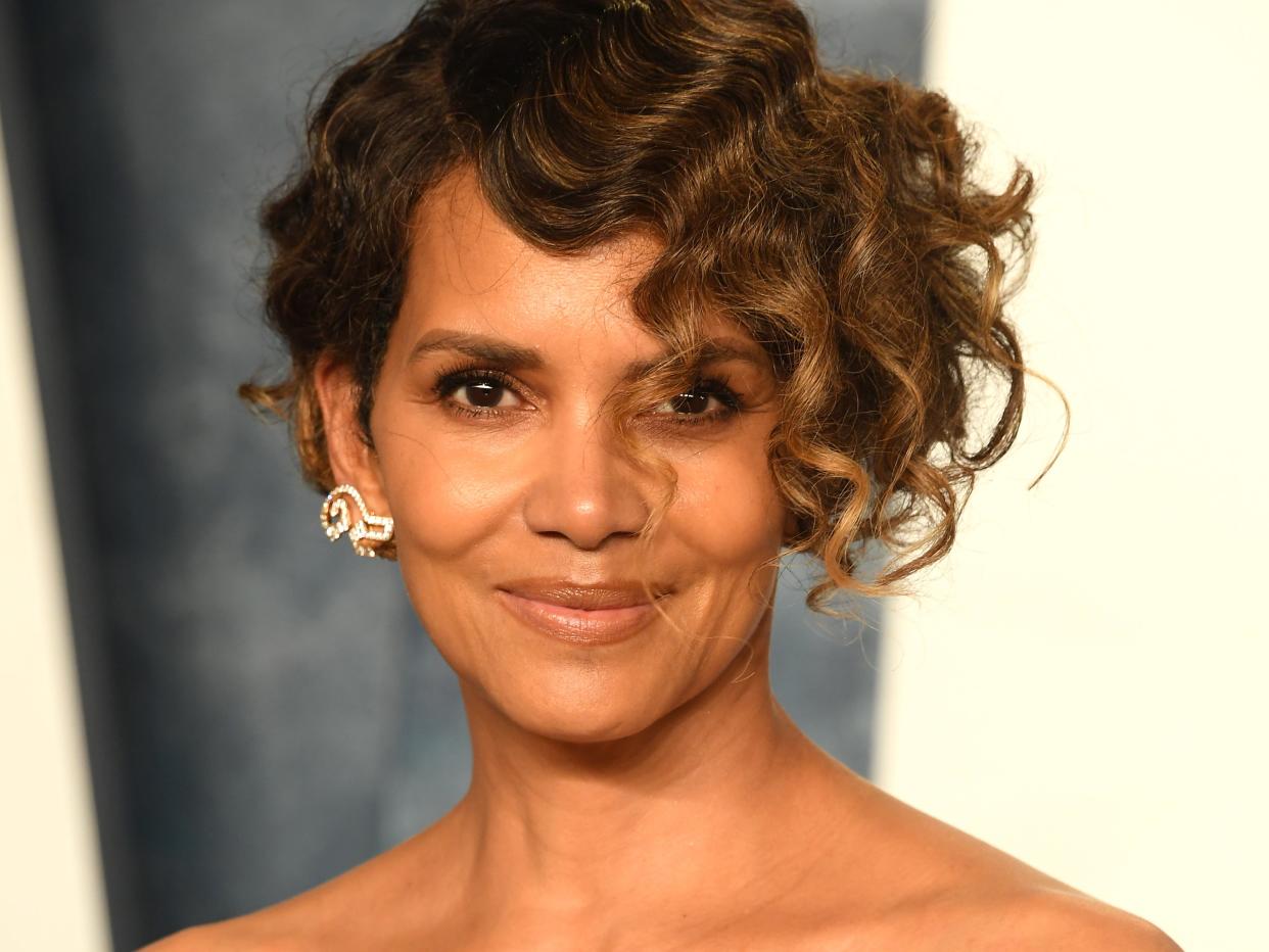 Halle Berry poses for photos on the red carpet in a black strapless gown with bow detailing at the bodice.