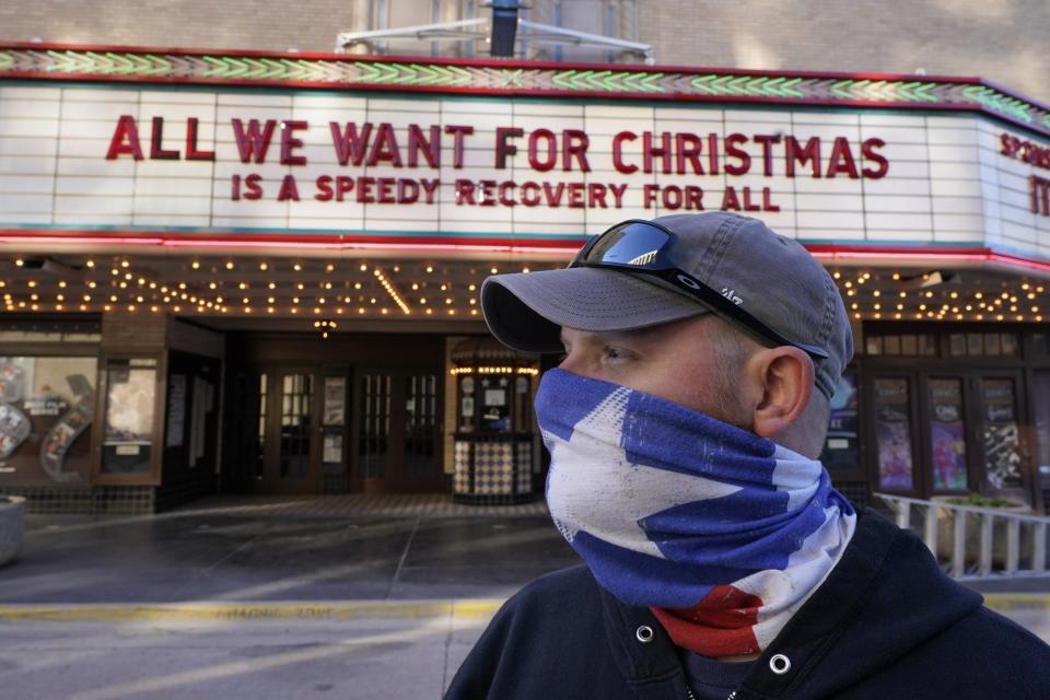 Employee Grayson Allred poses for a photo after putting up a message on the front marquee at the Paramount Theatre on Wednesday, Dec. 16, 2020, in Abilene, Texas. The theatre has closed down operations indefinitely due to rising cases of COVID-19 in the city. (AP Photo/Tony Gutierrez)