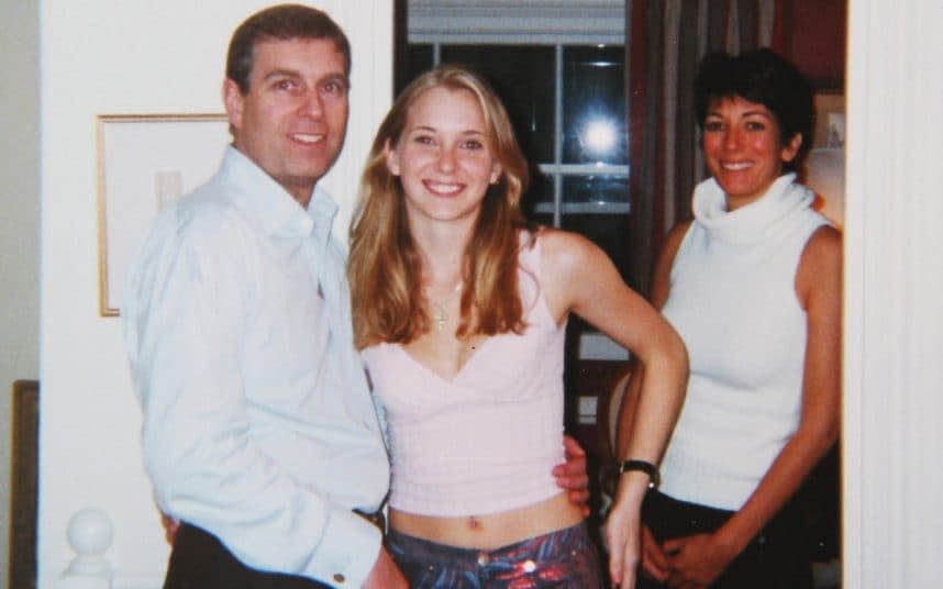 Prince Andrew smiling as he stands with his left arm around the waist of a young Virginia Roberts. It is alleged to have been taken in early 2001. Ghislaine Maxwell stands behind. - AKGS