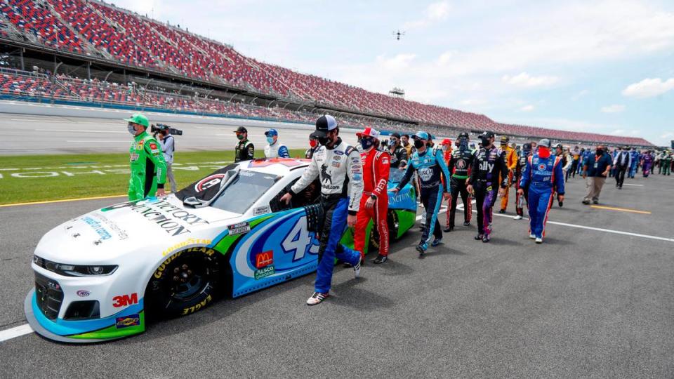 Nascar drivers and crews push the car of Bubba Wallace to the front of the field prior to the start of the NASCAR Cup Series auto race at the Talladega Superspeedway in Talladega Ala., Monday.