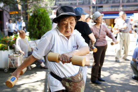 Elderly and middle-aged people exercise with wooden dumbbells during a health promotion event to mark Japan's "Respect for the Aged Day" at a temple in Tokyo's Sugamo district, an area popular among the Japanese elderly, Japan, September 18, 2017. REUTERS/Toru Hanai