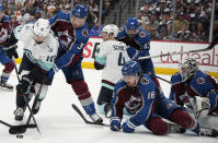 Seattle Kraken center Matty Beniers, left, fights to collect the puck as Colorado Avalanche defenseman Jack Johnson (3) and center Alex Newhook (18) cover in the second period of Game 7 of an NHL first-round playoff series Sunday, April 30, 2023, in Denver. (AP Photo/David Zalubowski)