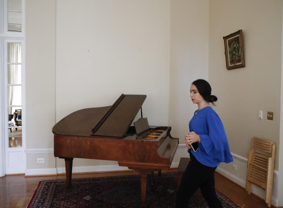 In this Sept. 17, 2019, photo, a staff member walks past a section of blank wall space above a piano where artwork once hung inside the Ambassador's residence in Washington. U.S. officials are investigating the possible looting from Venezuela of valuable European and Latin American artwork they believe is being quietly plundered by government insiders as Nicolas Maduro struggles to keep his grip on power. (AP Photo/Pablo Martinez Monsivais)