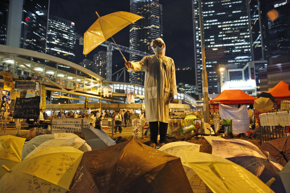 FILE - In this Oct. 9, 2014, file photo, a protester holds an umbrella during a performance on a main road in the occupied areas outside government headquarters in Hong Kong's Admiralty. The color yellow was closely associated with massive pro-democracy protests known as the Umbrella Movement. Umbrellas used as protection from pepper spray and tear gas gave the movement its name, and a yellow umbrella came to symbolize it. (AP Photo/Kin Cheung, File)