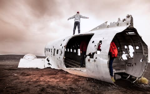 Tourists have their photo taken at the Sólheimasandur plane wreck - Credit: iStock