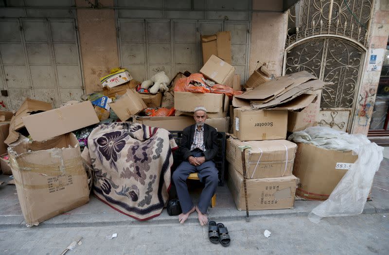 A man sits near goods at a market as Palestinians prepare for the upcoming holiday of Eid al-Fitr marking the end of Ramadan