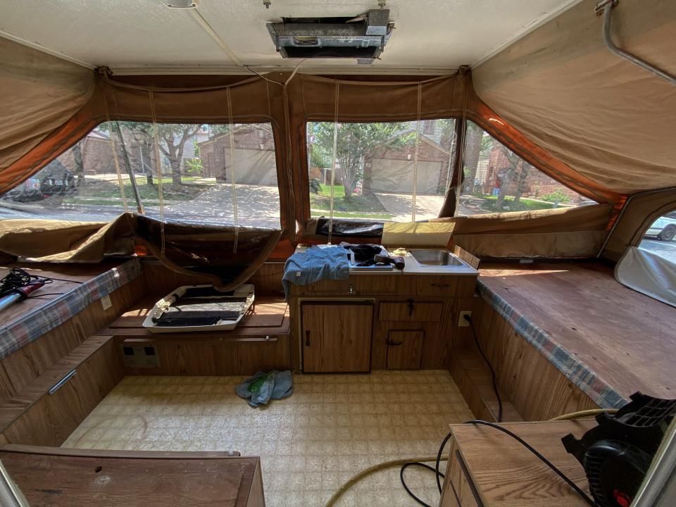 The neutral-colored interior of the pop-up camper with seat benches and cabinets