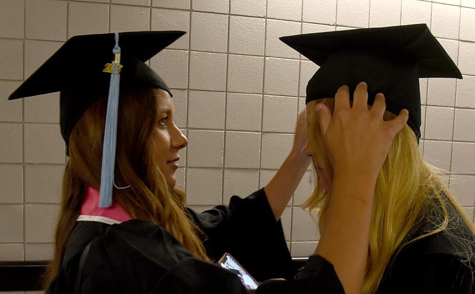 Alyssa Blumenshine, left, fixes Maggie Boland’s mortar board before they graduated with degrees in elementary education on Friday at Mizzou Arena.