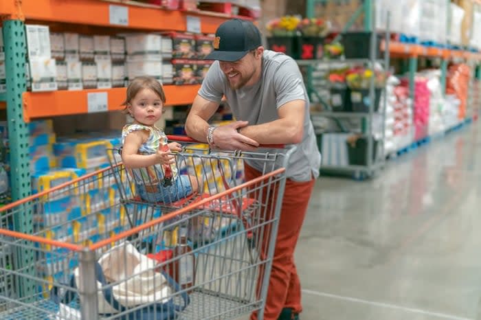 Person and child shopping warehouse store with shopping cart