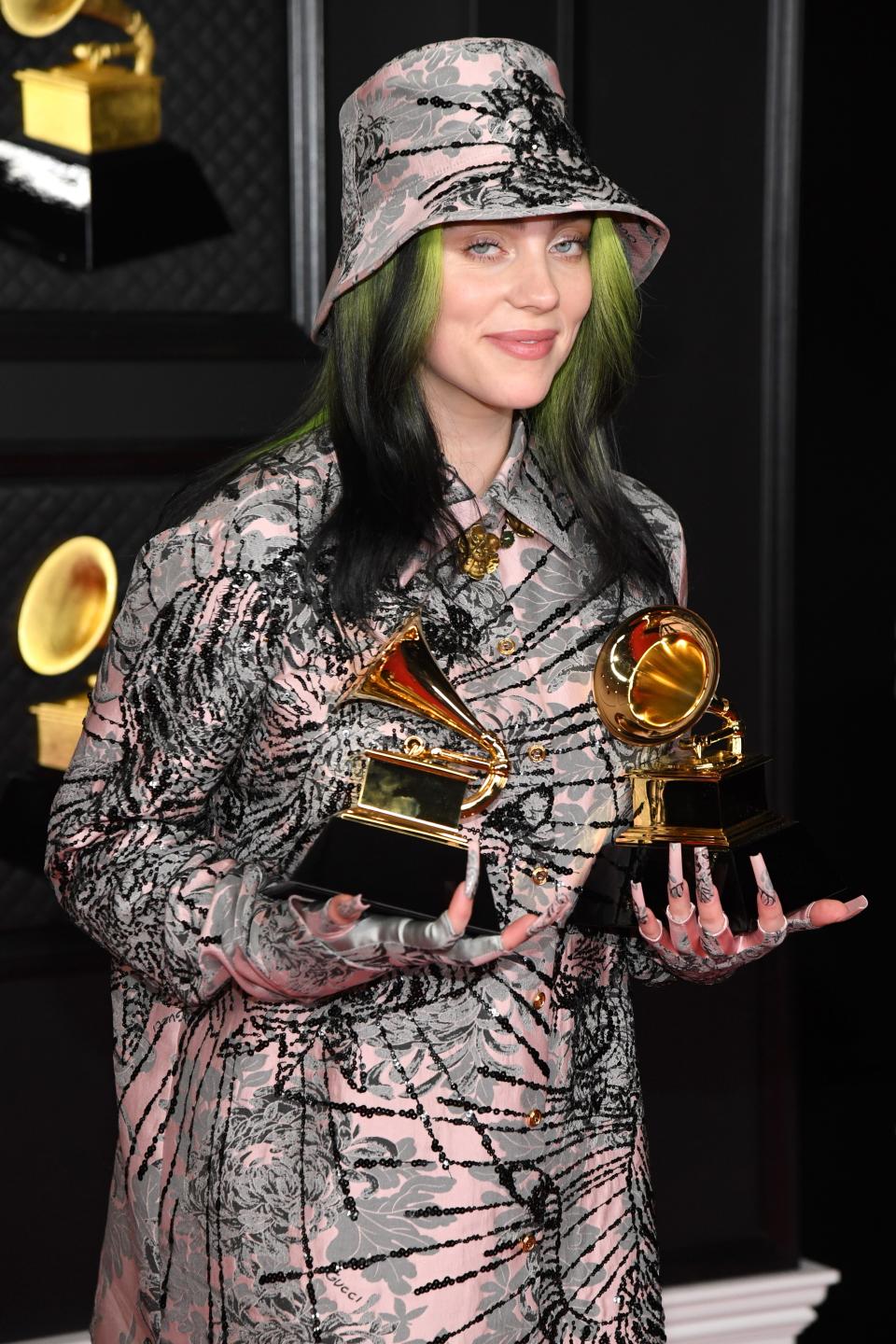 Billie Eilish posing with two Grammy Awards.