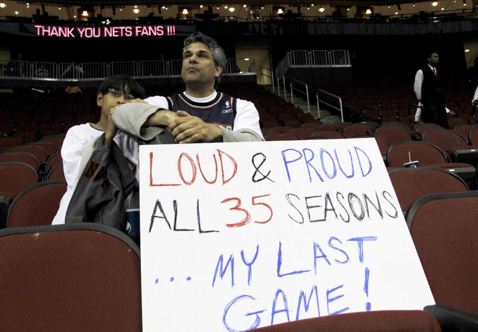 Bill Zarro, 45, right, of Teaneck, N.J., reacts as he and his 11-year-old son, Milan, sit in their seats at the end of an NBA basketball game between the New Jersey Nets and the Philadelphia 76ers, Monday, April 23, 2012, in Newark, N.J. The Nets, who played their last regular season home game, will pack up and move to Brooklyn. The 76ers won 105-87. (AP Photo/Julio Cortez)