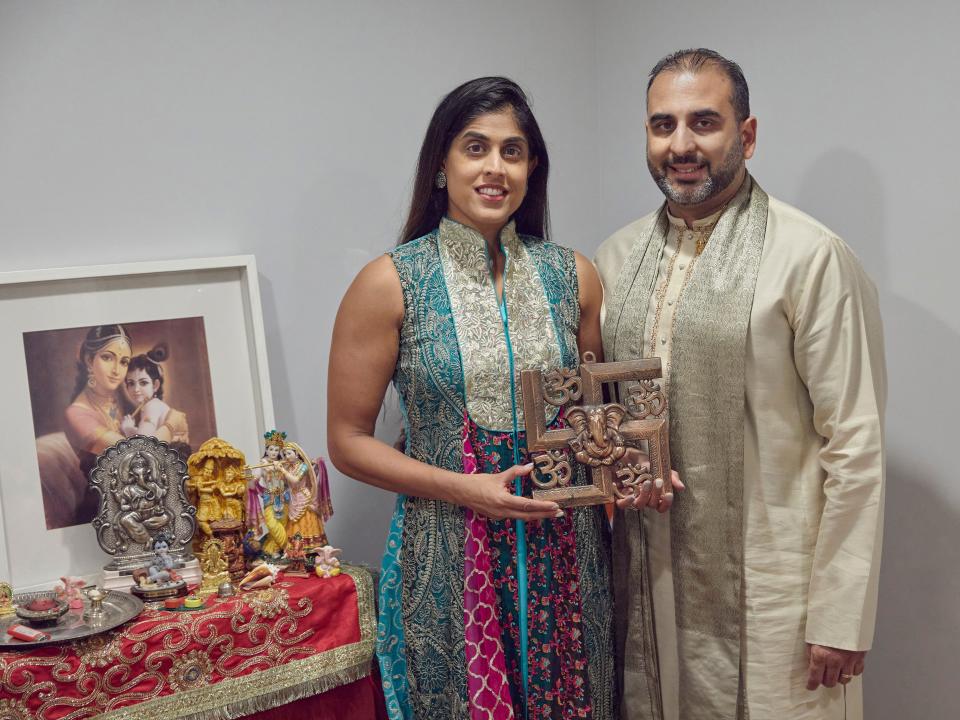 Sheetal Deo and her husband, Sanmeet Deo, hold a Hindu swastika symbol in their home in Syosset, N.Y., on Sunday, Nov. 13, 2022.