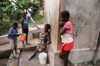 A girl fills a bucket at a water access point in in Jean-Rabel
