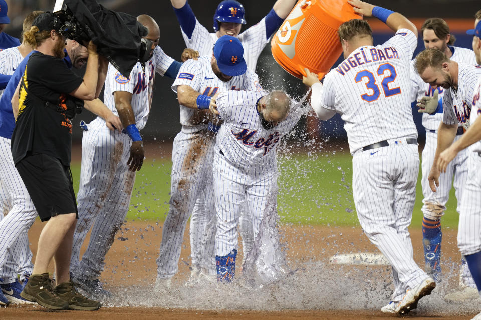 Teammates douse New York Mets' Luis Guillorme, center front, after he hit a walkoff RBI single during the 10th inning of a baseball game against the Los Angeles Dodgers at Citi Field, Sunday, July 16, 2023, in New York. (AP Photo/Seth Wenig)