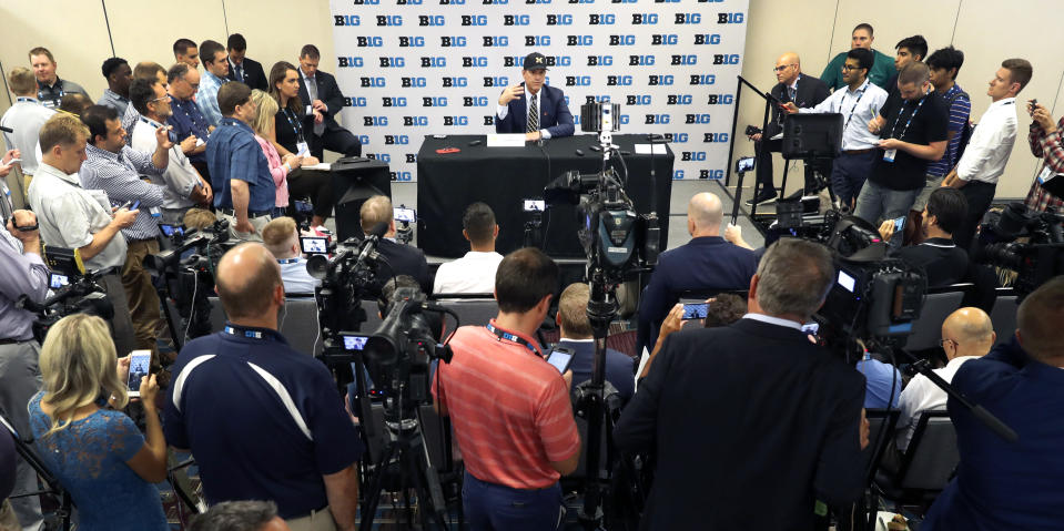 Michigan head coach Jim Harbaugh, back center, is surrounded by reporters and photographers during the Big Ten Conference NCAA college football media days Friday, July 19, 2019, in Chicago. (AP Photo/Charles Rex Arbogast)